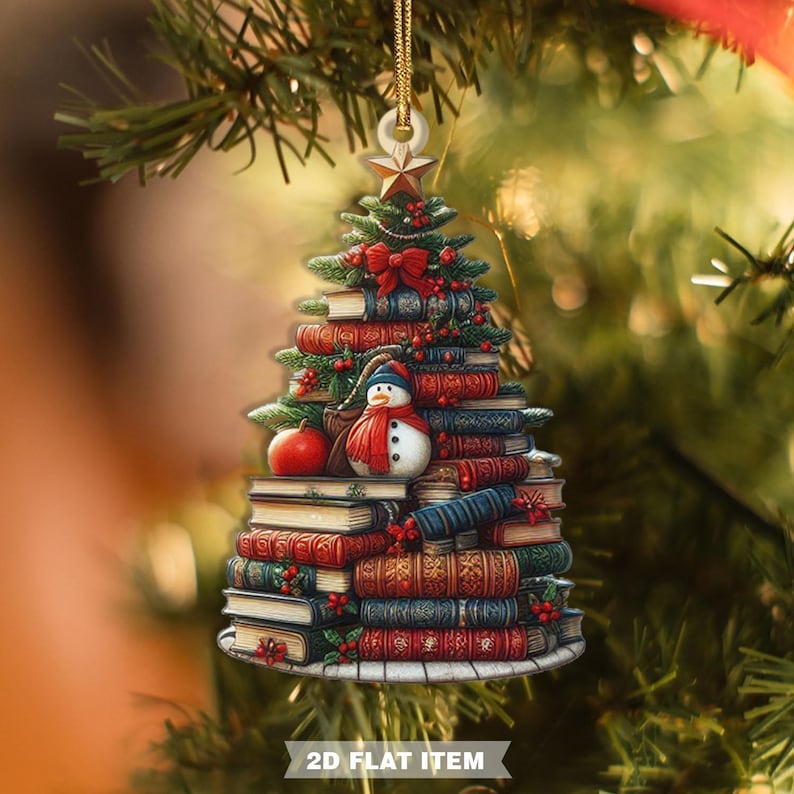 May include: Christmas tree ornament shaped like a stack of books, with a snowman, red bow, and star. The ornament is decorated with red berries and a small apple. The text "2D FLAT ITEM" is at the bottom.