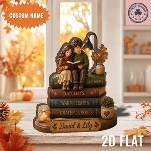 Puede incluir: Una figura decorativa de mesa que muestra a una pareja joven leyendo un libro sentada sobre una pila de cuatro libros titulados Fall Memories, Cozy Days, Warm Hearts y Grateful Souls. Incluye una pequeña lámpara, una vela y una suculenta.