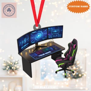 Könnte beinhalten: Ein Gaming-Ornament mit einem Schreibtisch mit drei Monitoren, einer Tastatur und einem Mauspad mit dem Text "YOUR NAME". Ein Gaming-Stuhl mit rosa und grünen Akzenten befindet sich neben dem Schreibtisch. Der Text "CUSTOM NAME" ist ebenfalls sichtbar.