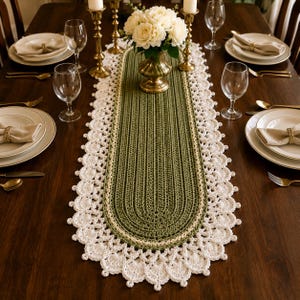 May include: An oval crochet table runner featuring a solid olive green center with a textured ribbed pattern, bordered by a thin cream-colored line and finished with an intricate, scalloped white lace edge that drapes along the table surface.