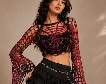May include: A long-sleeved crochet top featuring a dark red and black spiderweb pattern, worn over a solid black crop top. The garment has wide, flared sleeves and a scalloped hemline, paired with a black tiered mini skirt and a thin silver chain belt.