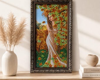 Könnte beinhalten: Ein rechteckiges Diamant-Gemälde, das eine Frau in einem langen Kleid zwischen herbstlichen Bäumen mit orangefarbenen, gelben und grünen Blättern zeigt. Das Kunstwerk ist in einem dunklen, verzierten Rahmen mit einem sich wiederholenden Rankenmuster.