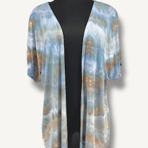 May include: A light blue and brown tie-dye open front cardigan with short sleeves.