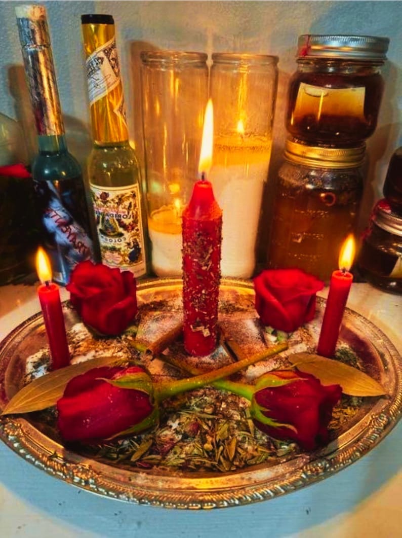 May include: A spiritual arrangement featuring lit red candles, red roses, and glass jars. The candles are placed on a silver tray with herbs and spices. Bottles with labels are in the background, creating a mystical ambiance.