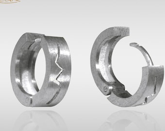May include: A pair of silver hoop earrings with a unique, textured design. The earrings have a hinged closure.