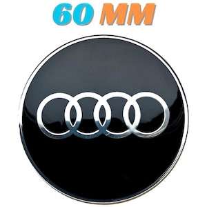 Op de afbeelding: Een zwart en zilveren auto-embleem met het Audi-logo, met vier in elkaar grijpende ringen. De tekst "60 MM" wordt boven het embleem weergegeven, wat een diameter van ongeveer 6 cm aangeeft.