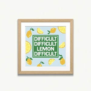 May include: A framed print with a light blue background and a pattern of yellow lemons. The text "Difficult Difficult Lemon Difficult" is written in green letters on a white background.