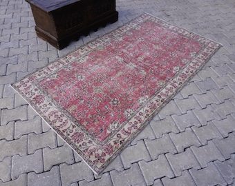 May include: A vintage pink and cream rug with a floral pattern. The rug has a faded, distressed look and is perfect for adding a touch of bohemian style to any room.