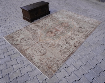 May include: A vintage rug with a beige background and a brown floral pattern. The rug has a distressed look and is perfect for adding a touch of bohemian style to any room.