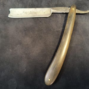 May include: A vintage straight razor with a wooden handle and a metal blade. The blade has the inscription "English Made" on it.