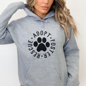 May include: A gray hooded sweatshirt with a black paw print graphic and the text "Adopt. Foster. Rescue." in a circle around the paw print.