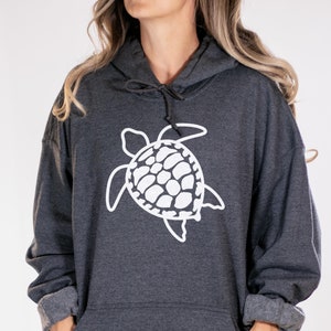 May include: A dark gray hooded sweatshirt with a white outline of a sea turtle on the front. The sweatshirt has a kangaroo pocket.