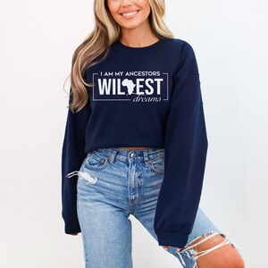 May include: A navy blue cropped sweatshirt with the text "I am my ancestors wildest dreams" and a white outline of the continent of Africa.