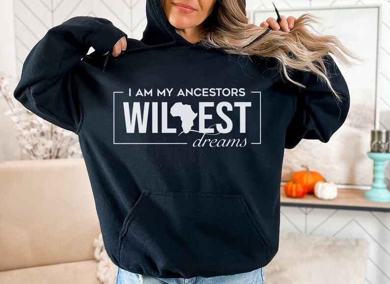 May include: Black hooded sweatshirt with a white graphic print that says "I am my ancestors wildest dreams" with an outline of the continent of Africa.