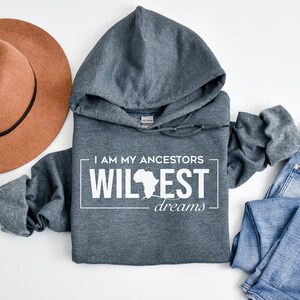May include: A dark gray hooded sweatshirt with the text "I am my ancestors wildest dreams" and an outline of the continent of Africa in white.