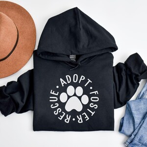 May include: Black hoodie with a white paw print and the text "Adopt. Foster. Rescue." in a circle.