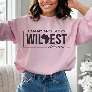 May include: Pink sweatshirt with the text "I am my ancestors wildest dreams" and a black silhouette of the continent of Africa.