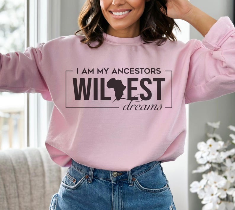 May include: Pink sweatshirt with the text "I am my ancestors wildest dreams" and a black silhouette of the continent of Africa.
