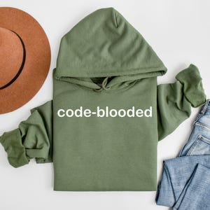 Op de afbeelding: Een groene hoodie met de tekst "code-blooded" in wit op de voorkant.