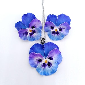 Könnte beinhalten: Ein Set aus drei blauen und violetten Stiefmütterchen-Ohrringen und einer Halskette. Die Blumen sind aus Polymer Clay gefertigt und haben ein realistisches Aussehen.