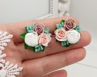 May include: A pair of delicate floral earrings featuring a cluster of pink and white polymer clay flowers with green leaves.