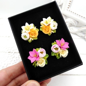 Op de afbeelding: Een set van vier paar polymer clay oorbellen met bloemmotieven. Elk paar heeft een andere kleurencombinatie van wit, roze, geel en groen.