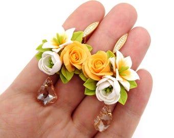 May include: A pair of floral earrings with orange and white flowers and crystal drops. The earrings are made of polymer clay and are handmade.