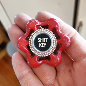 May include: A red metal water valve with a silver and black centre that says "SHIFT KEY".