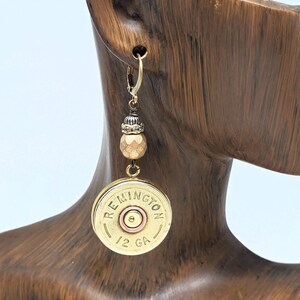 May include: Gold tone earrings featuring a brass shotgun shell with the text "Remington 12 GA" and a copper-colored bead.