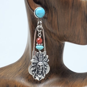 May include: Silver dangle earrings with a Native American chief head charm, turquoise and red beads, and a safety pin charm.