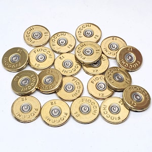 May include: A close-up of a pile of gold-colored shotgun shells with the word "Fiocchi" and the number "12" printed on them.