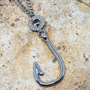 May include: A silver chain necklace with a silver bullet charm and a silver fishing hook pendant.