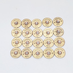 May include: A collection of twenty brass-colored 12-gauge shotgun shell casings. Each casing is stamped with the word "FIOCCHI", the number "12", and the letters "INT". The casings are arranged in a grid pattern against a white background.