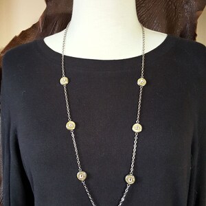 May include: A silver chain necklace with seven round gold bullet casings as accents.