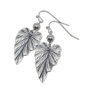 May include: Silver leaf earrings with a textured design. The earrings have a hook closure.