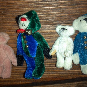 May include: Four small plush teddy bears in various colors and designs. A brown bear, a white bear, a blue and green bear, and a blue bear with a bell.