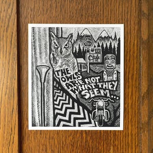 Op de afbeelding: Zwart-witte illustratie van een uil met de tekst "The owls are not what they seem." De illustratie bevat ook een cafébord, een bergketen en een motorfiets.