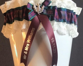 May include: A white lace garter with a burgundy ribbon and a tartan bow. The ribbon is personalized with the text "Mr & Mrs Williams" and the date "13.11.22".