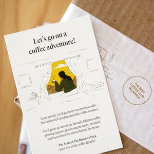 Pu&ograve; includere: Un biglietto bianco con un'illustrazione disegnata a mano di una persona che guarda fuori da una finestra mentre tiene una tazza di caff&egrave;. Il testo sul biglietto dice "Let's go on a coffee adventure!" e "Ogni mese, potrai provare un caff&egrave; eccezionale di torrefattori canadesi specializzati. Ti imbarcherai in un'avventura attraverso diverse regioni di coltivazione del caff&egrave;, metodi di lavorazione, variet&agrave; e imparerai le storie dietro i chicchi. - Il team di The Roasters Pack (i tuoi nuovi amici del caff&egrave;)"