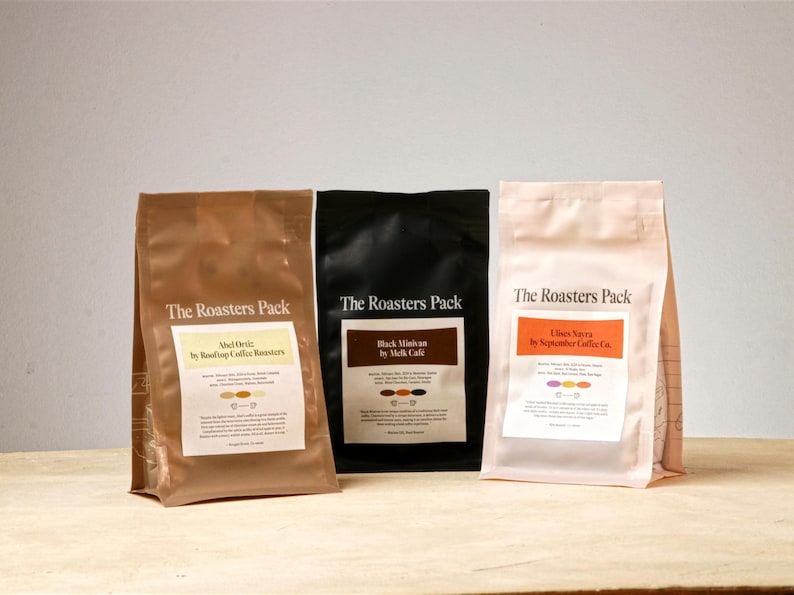 Pu&ograve; includere: Tre sacchetti di carta marroni, neri e bianchi con la scritta "The Roasters Pack" stampata sul davanti. Ogni sacchetto presenta un nome di miscela di caff&egrave; e un torrefattore diversi: "Adrie" di "Rooftop Coffee Roasters", "Black Minivan" di "Melk Cafe" e "Ultras Navra" di "September Coffee Co."