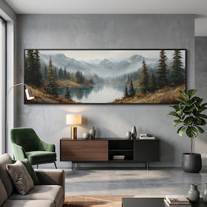 May include: A large landscape painting in a black frame depicts a serene lake surrounded by evergreen trees and mountains. The artwork features a muted color palette with shades of green, brown, and gray, creating a tranquil atmosphere. The painting is displayed above a modern console.