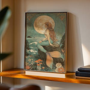 May include: Framed art print featuring a mermaid sitting on a rock, gazing at a full moon. The artwork has a vintage style with a color palette of teal, orange, and beige. The mermaid has long red hair and a teal tail. The background includes ocean waves and flowers.