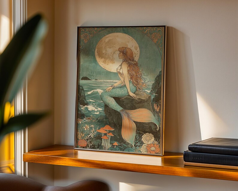 May include: Framed art print featuring a mermaid sitting on a rock, gazing at a full moon. The artwork has a vintage style with a color palette of teal, orange, and beige. The mermaid has long red hair and a teal tail. The background includes ocean waves and flowers.
