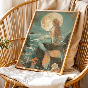 May include: A framed art print featuring a mermaid sitting on a rock, with a full moon in the background. The mermaid has long red hair and a turquoise tail. The artwork is in a vintage style, with muted colors and a wooden frame.