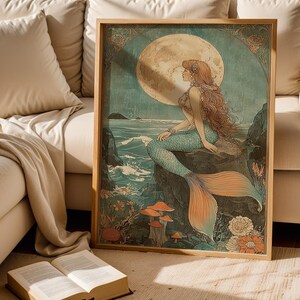 May include: A framed art print featuring a mermaid with long red hair, a turquoise tail, and a seashell top, sitting on a rock. The background includes a full moon, ocean waves, and colorful flowers. The artwork is in a vintage style.