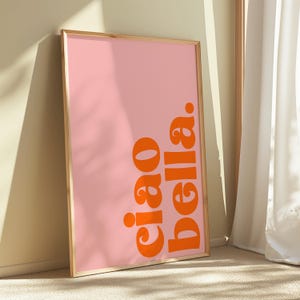 May include: A framed pink poster with the text "ciao bella" in orange.