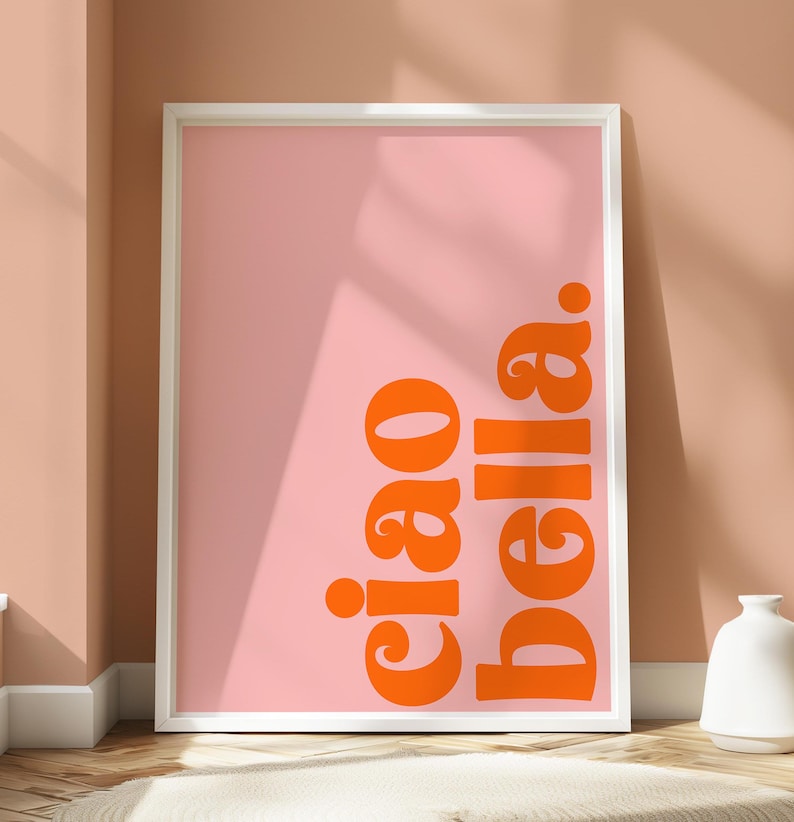 May include: A white framed poster with a pink background and the text "ciao bella" in orange.