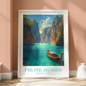 May include: A framed print of the Phi Phi Islands in Thailand. The image shows a turquoise bay surrounded by towering cliffs and lush greenery. A wooden boat with a red bow is in the foreground. The text "PHI PHI ISLANDS THAILAND" is at the bottom.