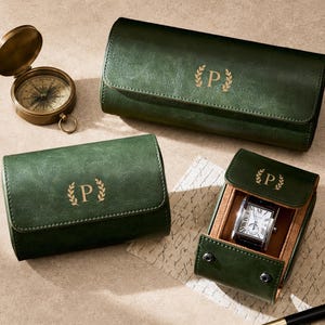 May include: Three dark green watch rolls with a gold letter P inside a laurel wreath emblem. One roll is open, revealing a silver wristwatch with a white face and black Roman numerals. A brass compass and a black pen are placed nearby.