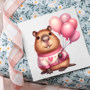 Puede incluir: Una tarjeta cuadrada con un dibujo de una marmota sosteniendo globos rosas. La marmota lleva un su&eacute;ter rosa con dise&ntilde;os de corazones. La tarjeta est&aacute; sobre una superficie con estampado floral y una cinta rosa.